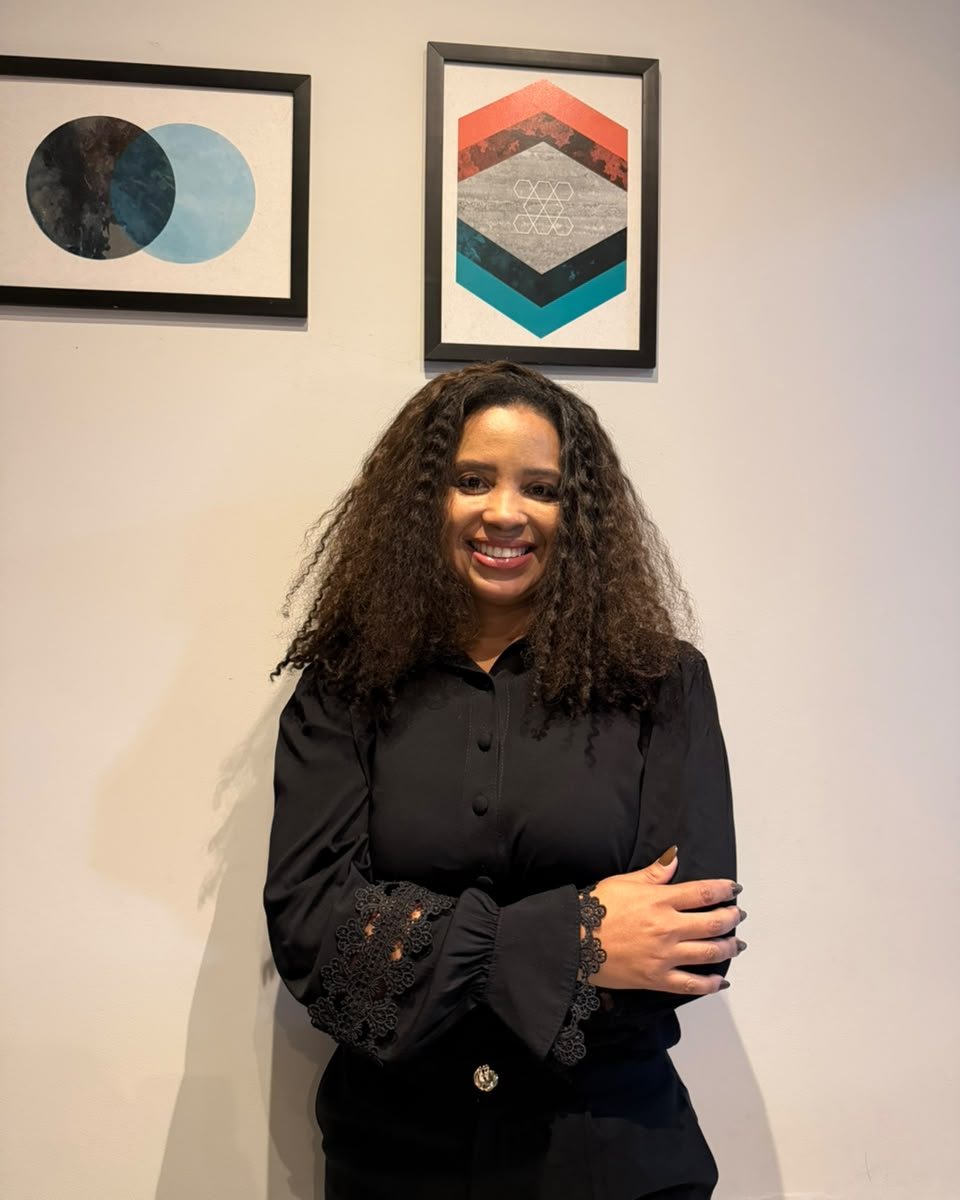 Viviane Tobias de braços cruzados, sorrindo, em frente a dois quadros geométricos